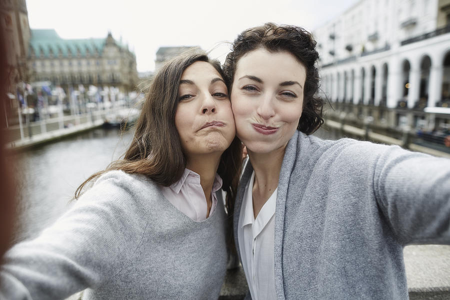 Portrait of two playful young women taking selfie Photograph by Oliver Rossi