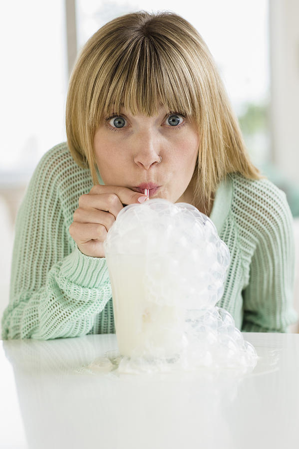 Portrait of woman blowing bubbles in milkshake Photograph by Jamie Grill