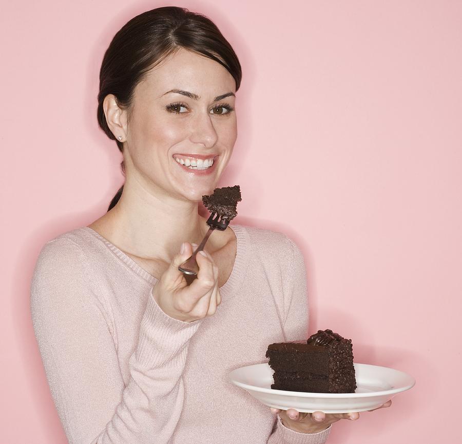 Portrait of woman eating cake Photograph by Tetra Images