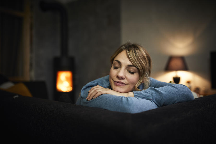 Portrait of woman relaxing on couch at home in the evening Photograph by Westend61
