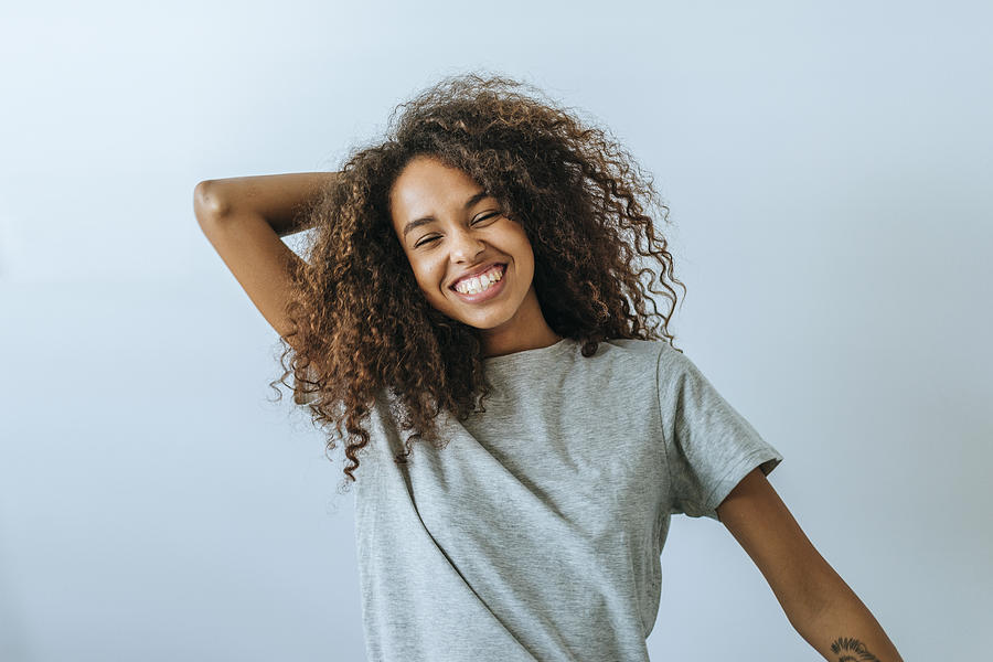 Portrait of woman with afro hair smiling with white wall background Photograph by F.J. Jimenez