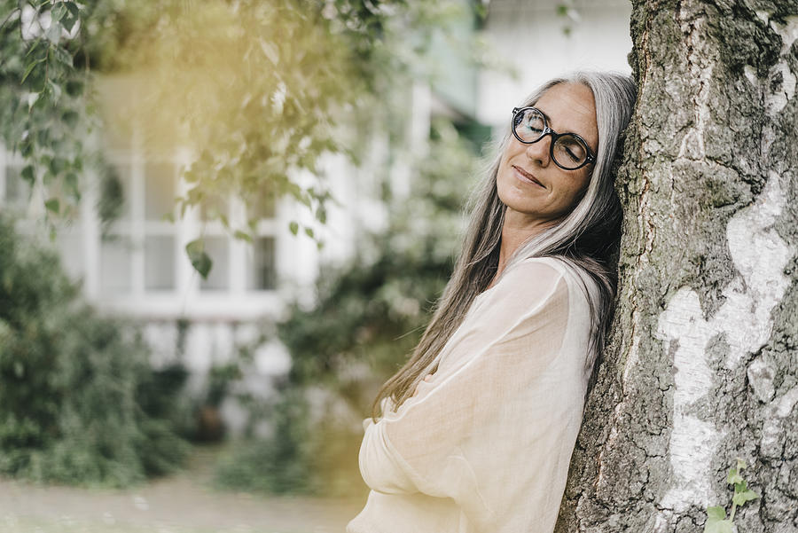 Portrait of woman with eyes closed leaning against tree trunk Photograph by Westend61