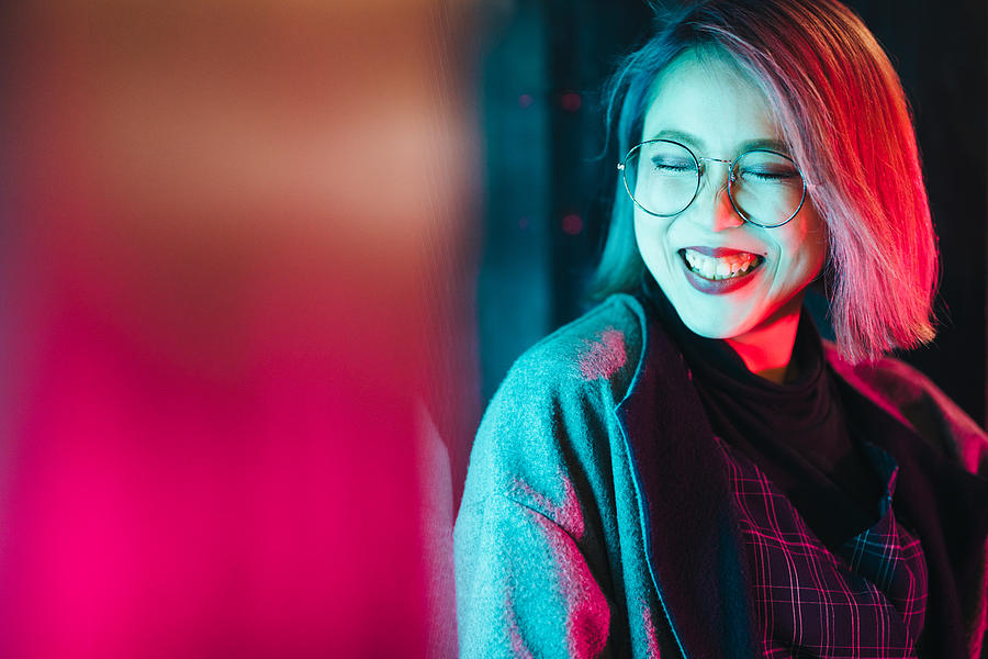 Portrait of young and happy woman lit up by neon lights Photograph by Recep-bg