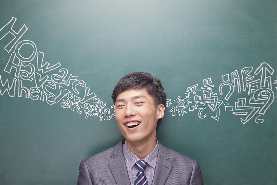 Portrait of young businessman in front of black board with Chinese and English script Photograph by XiXinXing