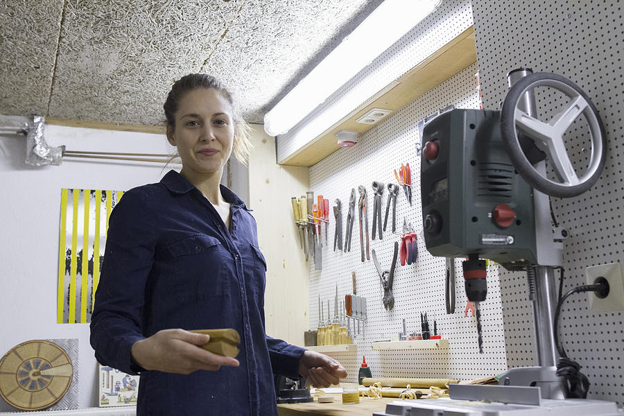 Portrait of young female carpenter at workbench in workshop Photograph by Sigrid Gombert