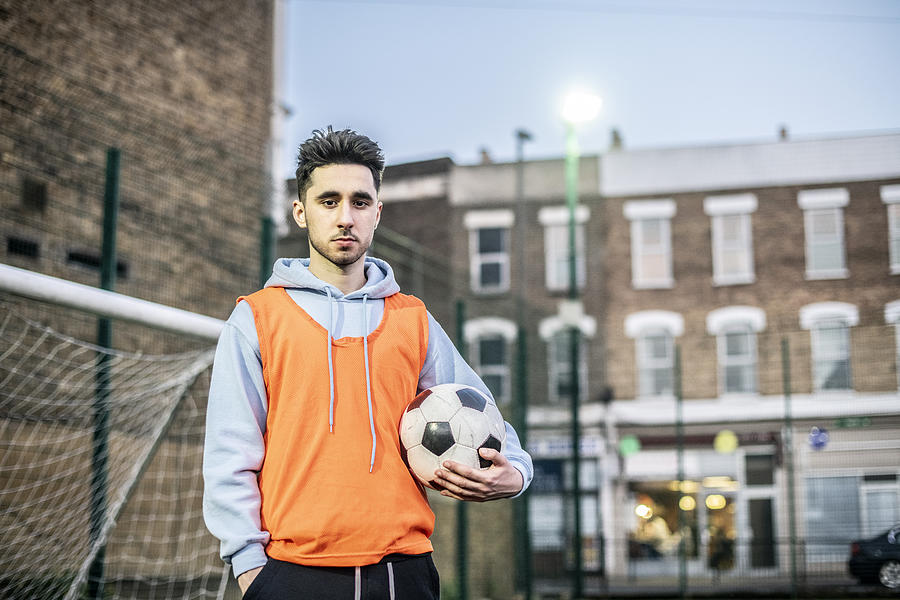 Portrait of young man in football bib holding ball Photograph by JohnnyGreig
