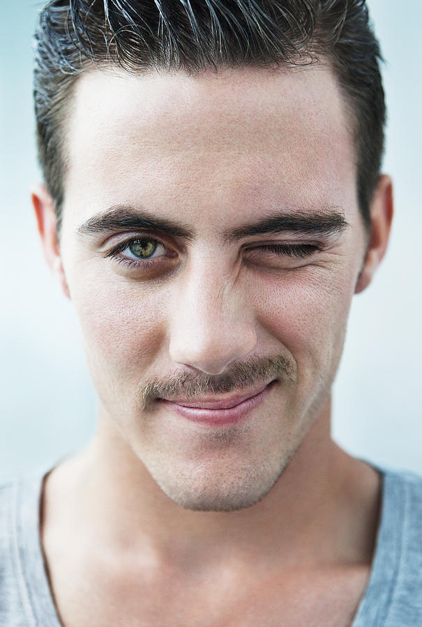 Portrait of young man with moustache, winking Photograph by Dimitri Otis