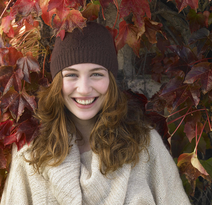Portrait of young woman against autumn leaves. Photograph by Dougal Waters