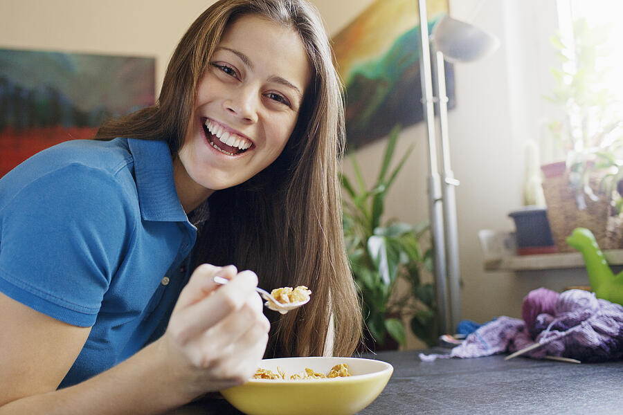 Portrait of young woman eating cereal Photograph by Oliver Rossi
