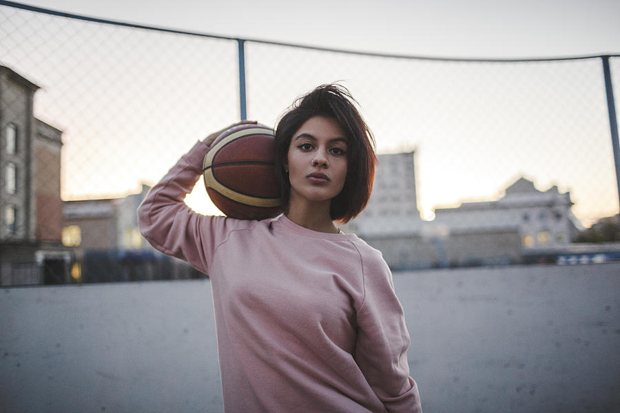 Portrait of young woman holding basketball outdoors Photograph by Westend61
