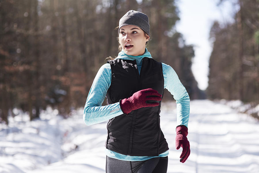 Portrait of young woman jogging in winter forest Photograph by Westend61
