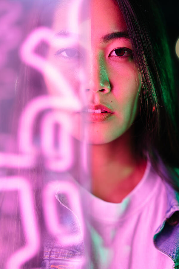 Portrait of young woman lit by pink neon light Photograph by Recep-bg