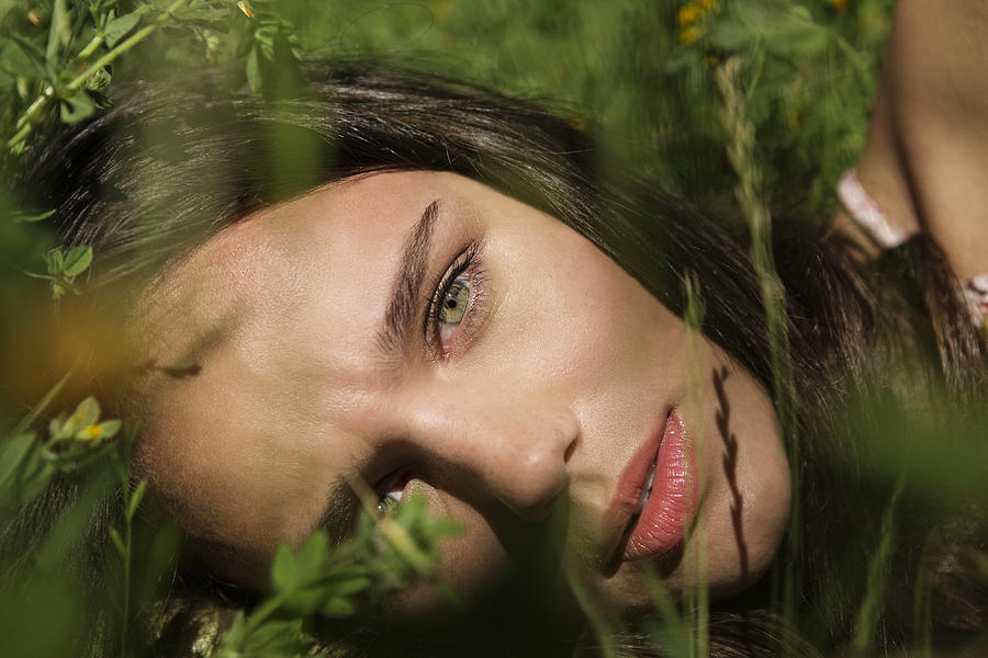 Portrait of young woman lying on grass Photograph by Tomas Rodriguez