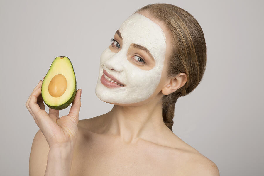 Portrait of young woman wearing face mask, holding avocado Photograph by Imperia Staffieri
