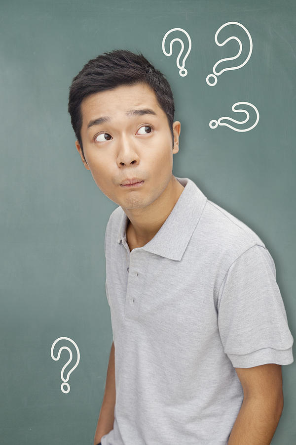 Portrait young man in front of blackboard with question marks Photograph by XiXinXing