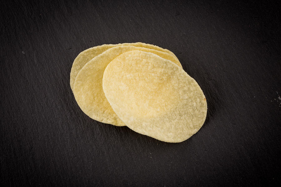 Potato chips on a black Photograph by R.Tsubin