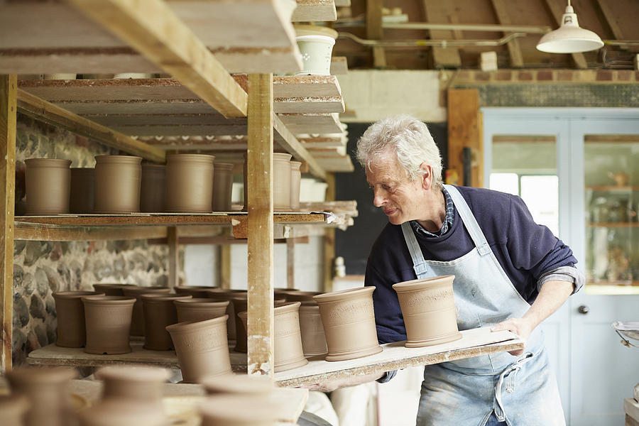 Potter moving boards of pots Photograph by Richard Drury