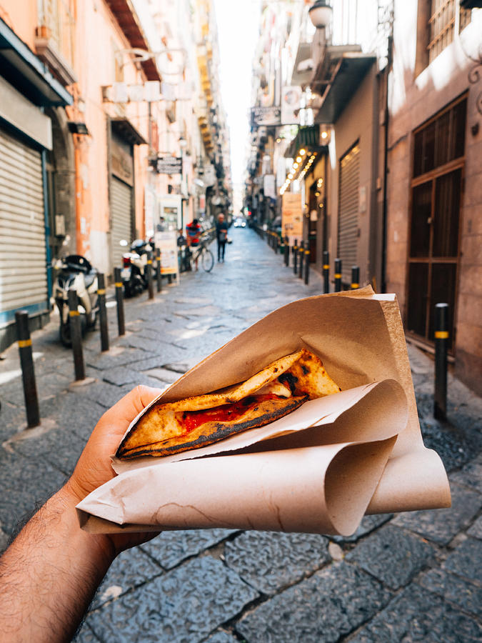 Pov view of a man eating a typical Pizza a portafoglio in Naples, Italy Photograph by FilippoBacci