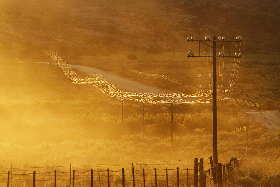 Power lines on road in grassy remote landscape Photograph by Jeremy Woodhouse