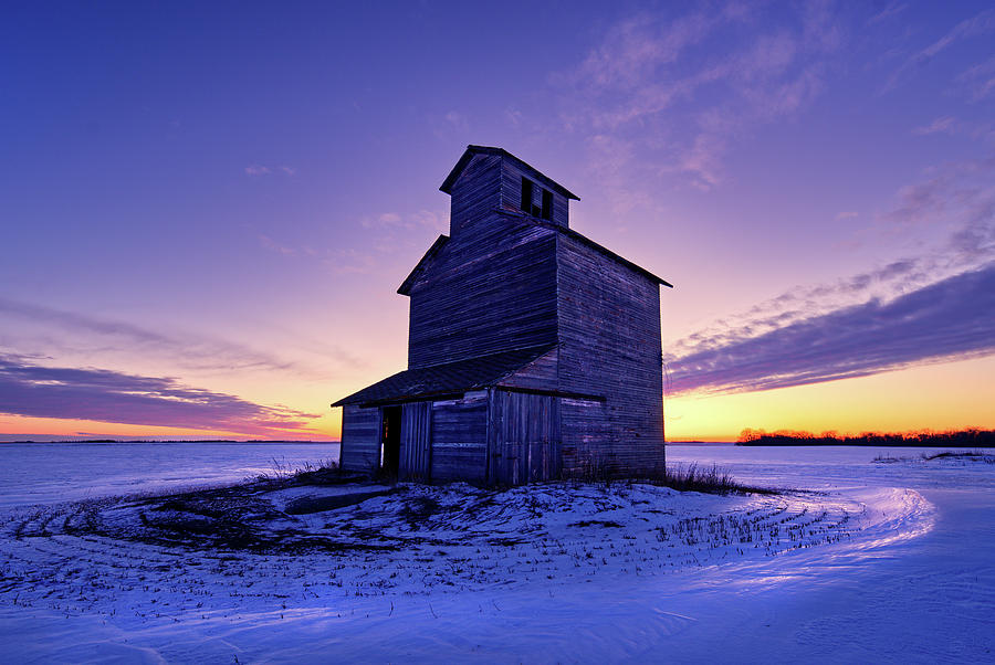 Prairie Sentinel - Lone abandoned grain elevator in ND snowscape after sunset Photograph by Peter Herman