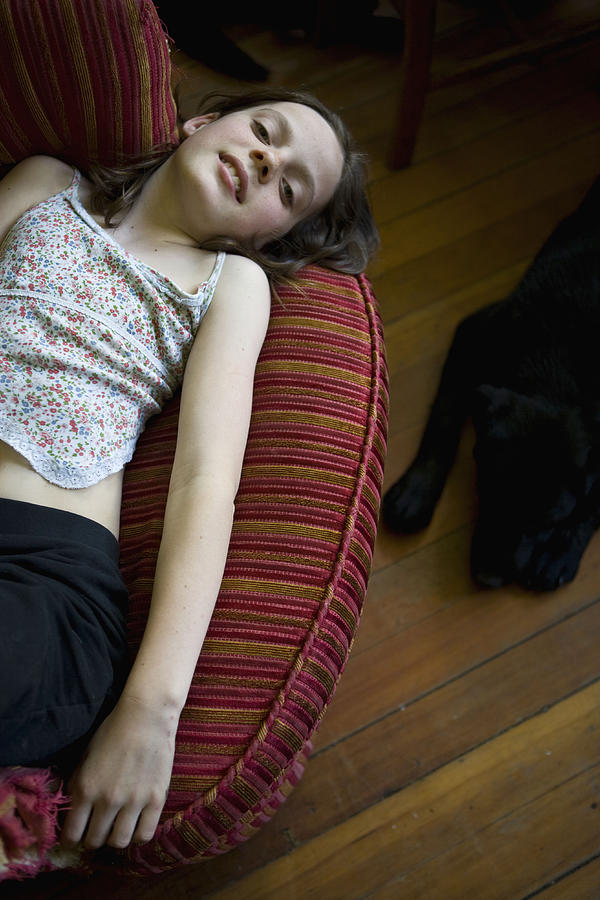 Pre-teen girl lying on chair in living room Photograph by Jeff Randall