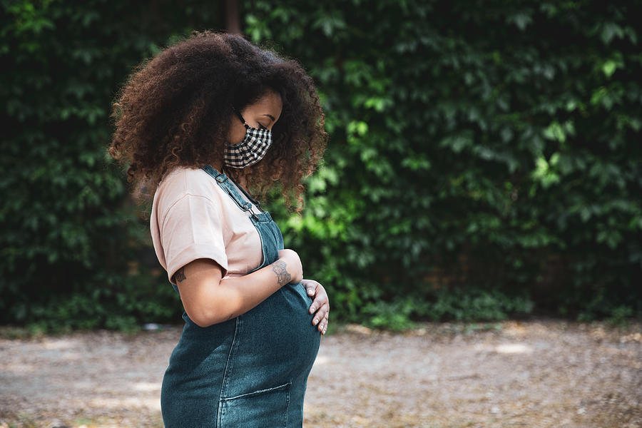 Pregnant afro hair woman in the city wearing a cloth protective mask Photograph by LeoPatrizi
