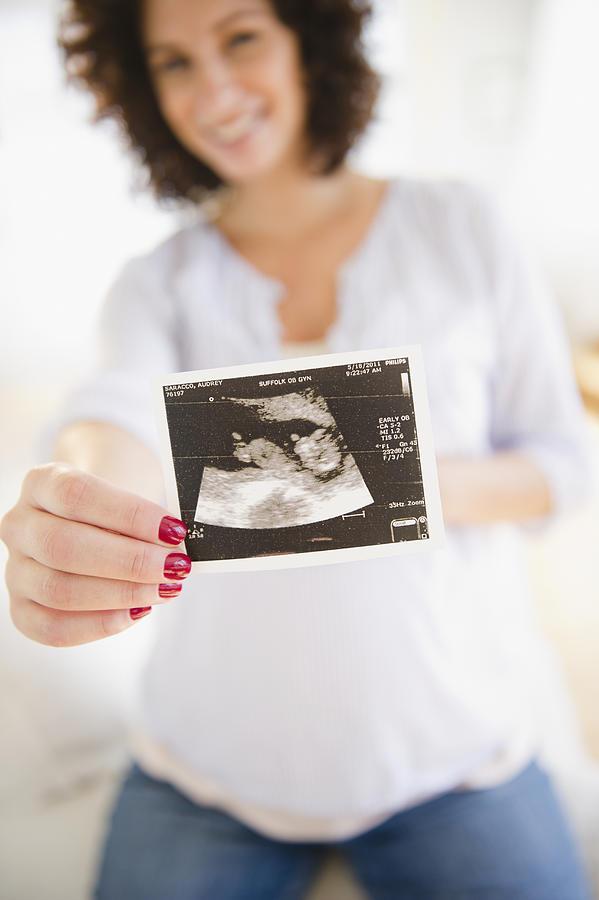 Pregnant woman holding ultrasound Photograph by Jamie Grill