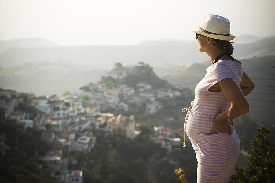 Pregnant woman standing with hand on hip, mountains in background Photograph by Johner Images - Kullman, Jonas