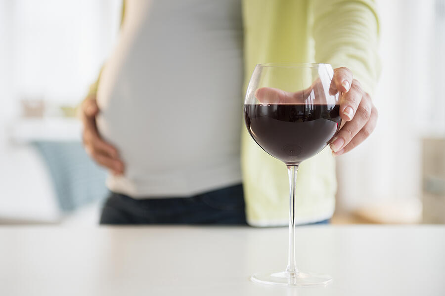 Pregnant woman with glass of red wine Photograph by Jamie Grill