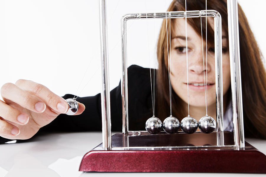 Pretty brunette playing with Newtons Cradle executive toy Photograph by RapidEye