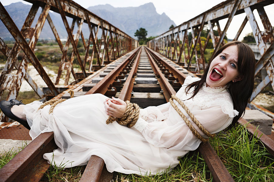 Pretty girl in period dress tied to railroad bridge, screaming Photograph by RapidEye