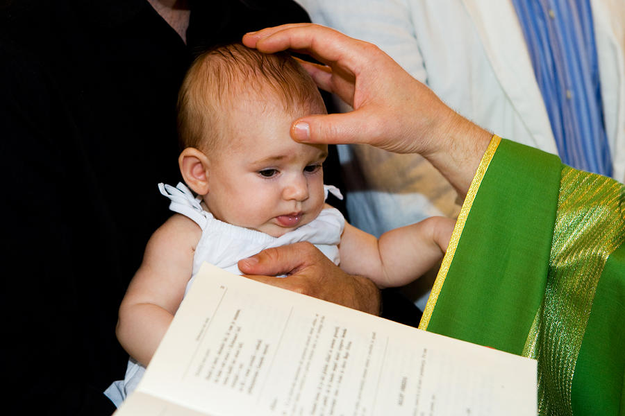 Priest is baptizing little baby in church. Photograph by Choja