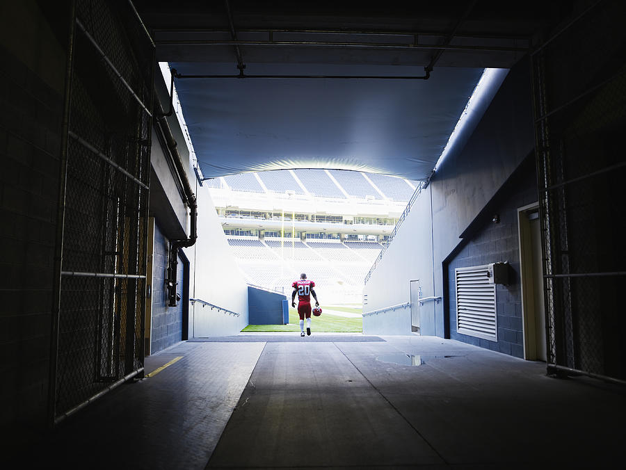 Professional football player walking into stadium Photograph by Thomas Barwick
