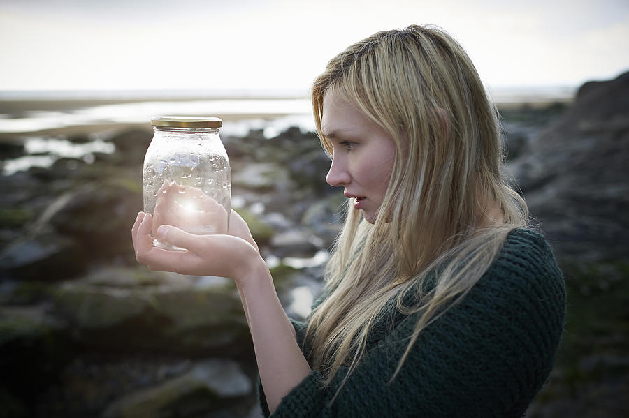 Profile of woman holding jam jar with glow. Photograph by Dougal Waters