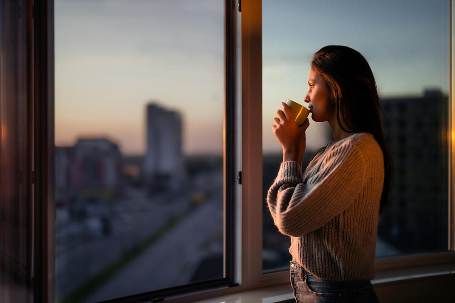 Profile view of beautiful woman drinking coffee by the window. Photograph by Skynesher