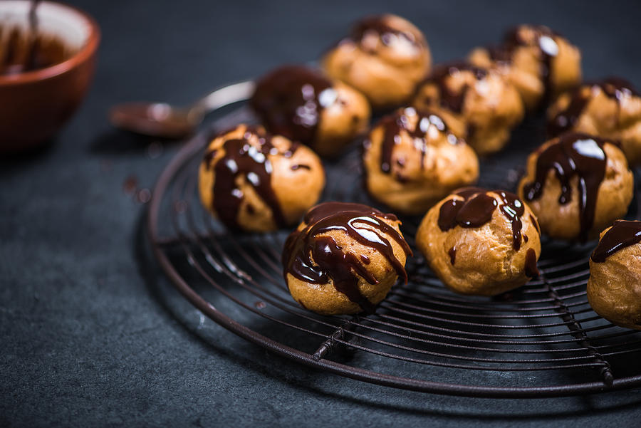 Profiteroles Eclairs Resting On Cooling Rack Photograph by Merc67