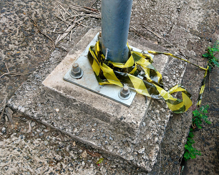 Public light pole base, fixed to the floor with screws, and remnants of signaling tape. Photograph by CRMacedonio