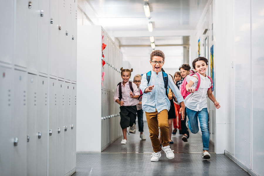 Pupils Running Through School Corridor Photograph by LightFieldStudios