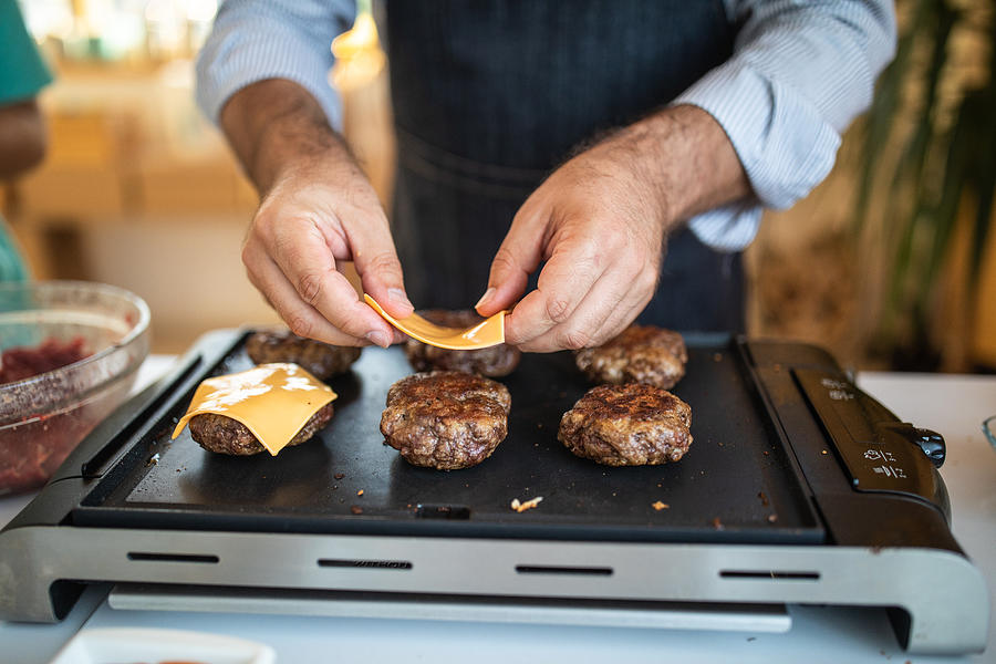 Putting cheese on burgers Photograph by Miodrag Ignjatovic
