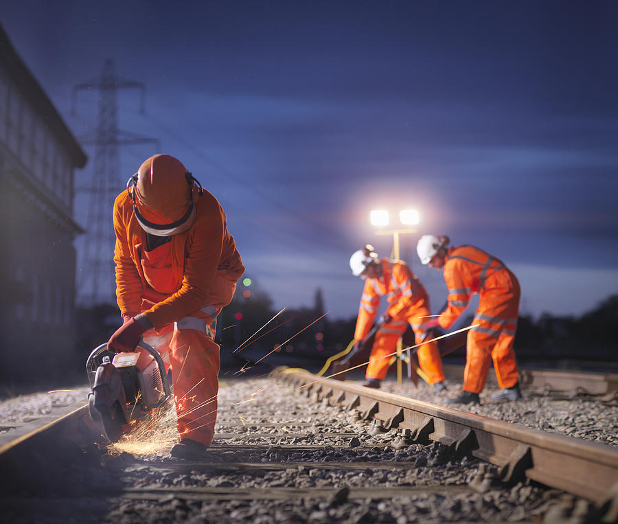 Railway maintenance workers using grinder on track at night Photograph by Cultura/Monty Rakusen