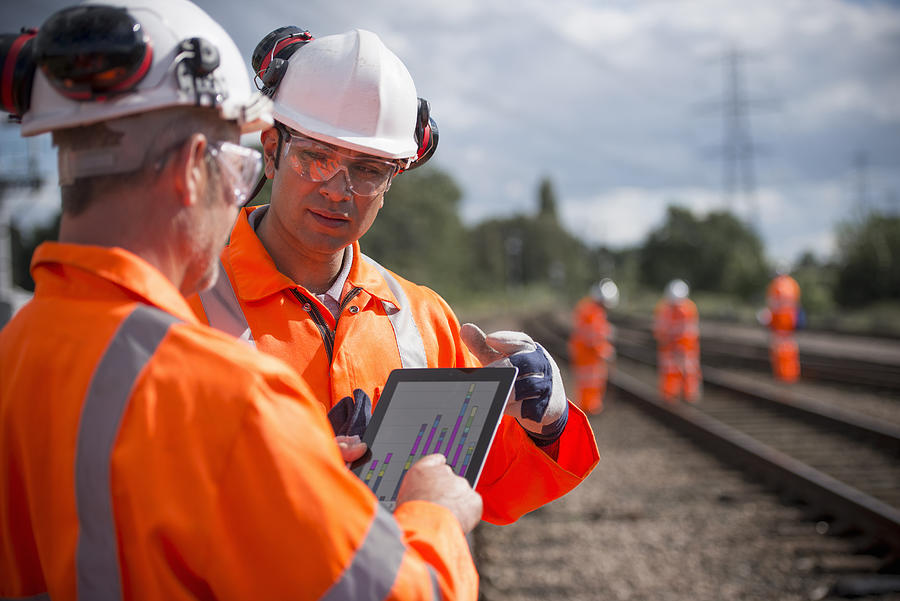 Railway workers using digital tablet to discuss work Photograph by Monty Rakusen