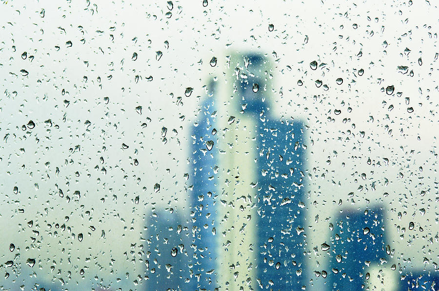 Rain drops on window, out of focus buildings in background Photograph by Ingo Jezierski