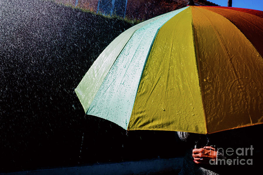Rain falls on an umbrella among sun rays, dark background in bla Photograph by Joaquin Corbalan