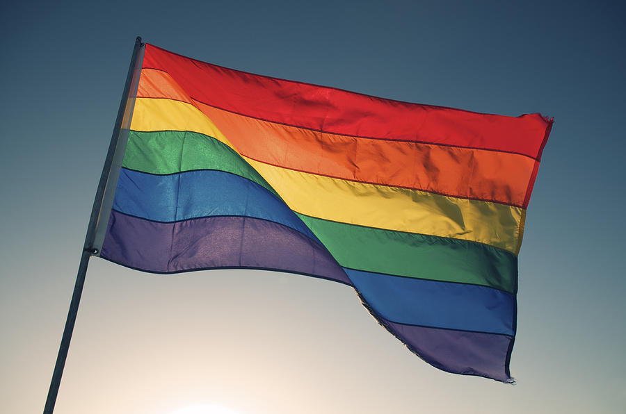 Rainbow Gay Pride Flag Waving Backlit by Bright Sun Sky Photograph by PeskyMonkey