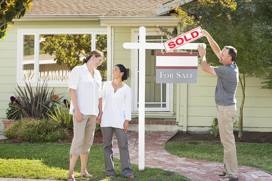 Real estate agent hanging sign outside house Photograph by Sollina Images