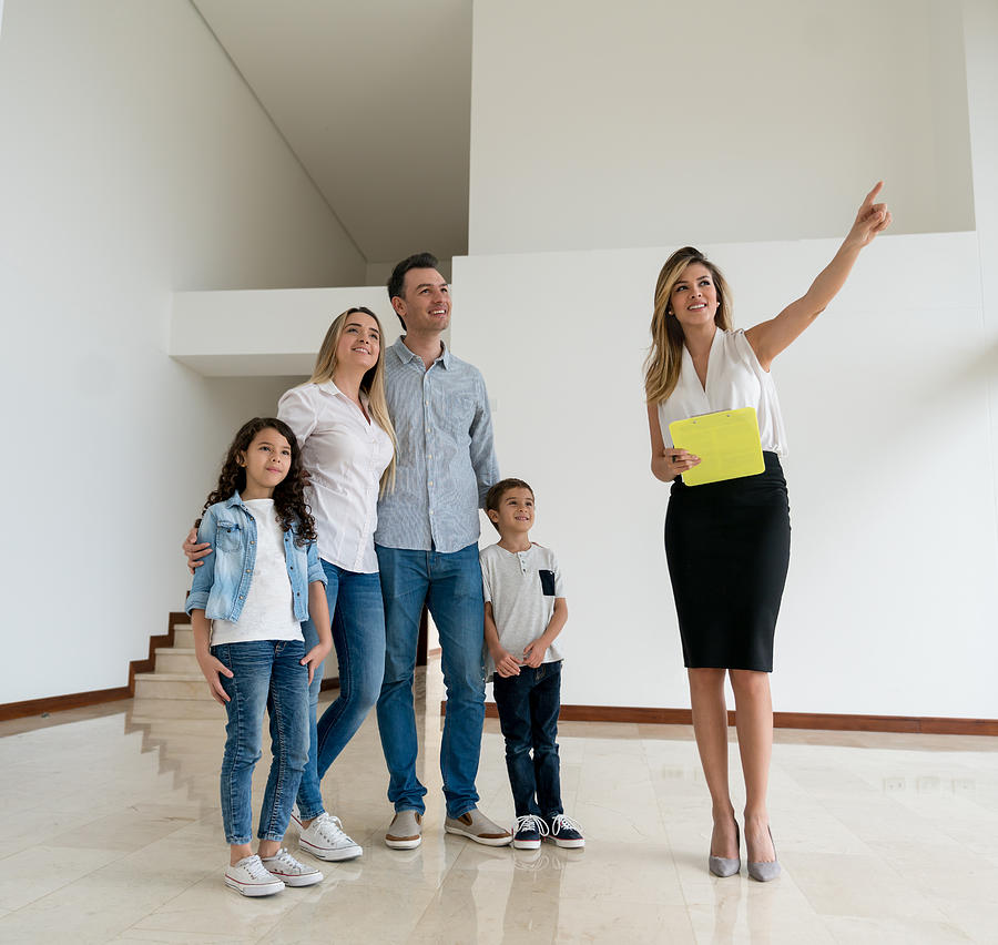 Real estate agent showing a house to a family Photograph by Andresr
