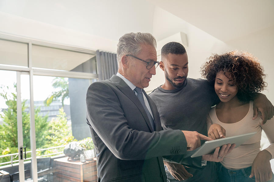 Real estate agent showing a property to an African American couple Photograph by Andresr