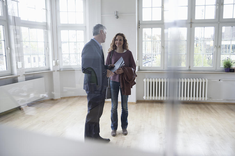 Real estate agent talking to client in empty apartment Photograph by Westend61