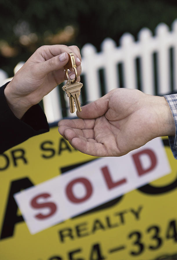 Realtor handing house keys to new owner Photograph by Comstock Images