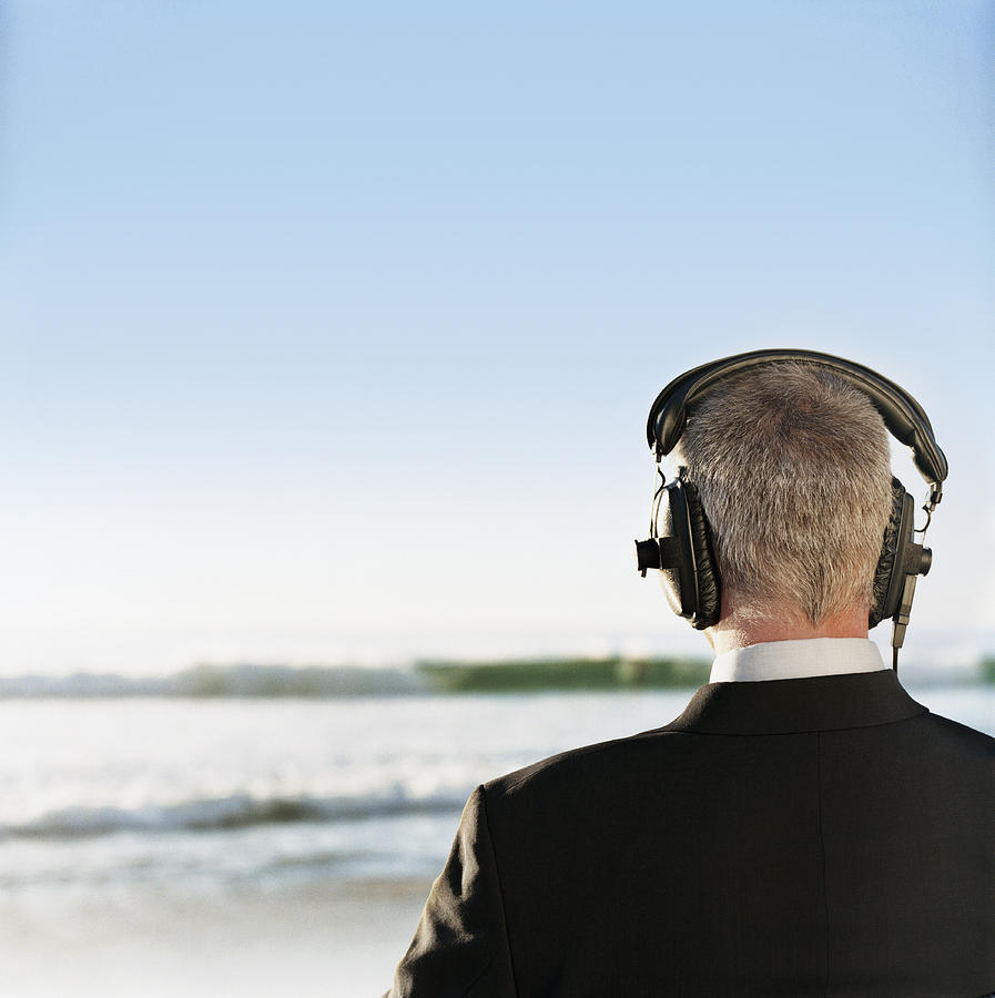 Rear View of a Businessman Standing by the Sea Wearing Headphones Photograph by John Cumming